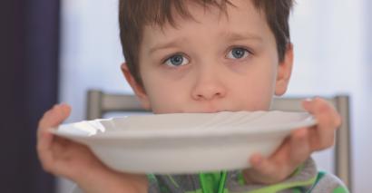 Hungry boy holds up empty plate