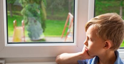 Young boy, staring sadly out window at playground
