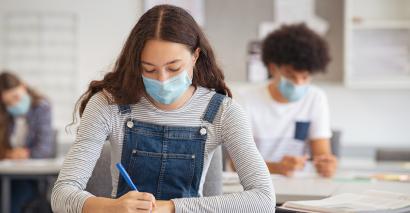 Teenage girl revising in classroom wearing a facemask