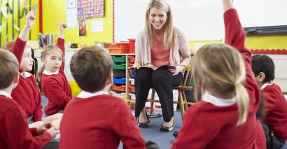 Teacher Surrounded By Engaged Pupils With Reading Activities