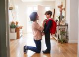 Mother adjusts son's uniform for first day at new school