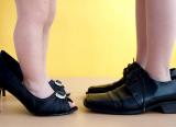 Two young children, standing in adults' shoes